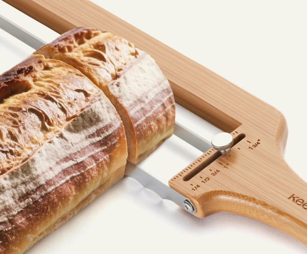 How Long Should Sourdough Cool Before Cutting? Close-up of a bread slicer guide and thickness knob beside a cut loaf.