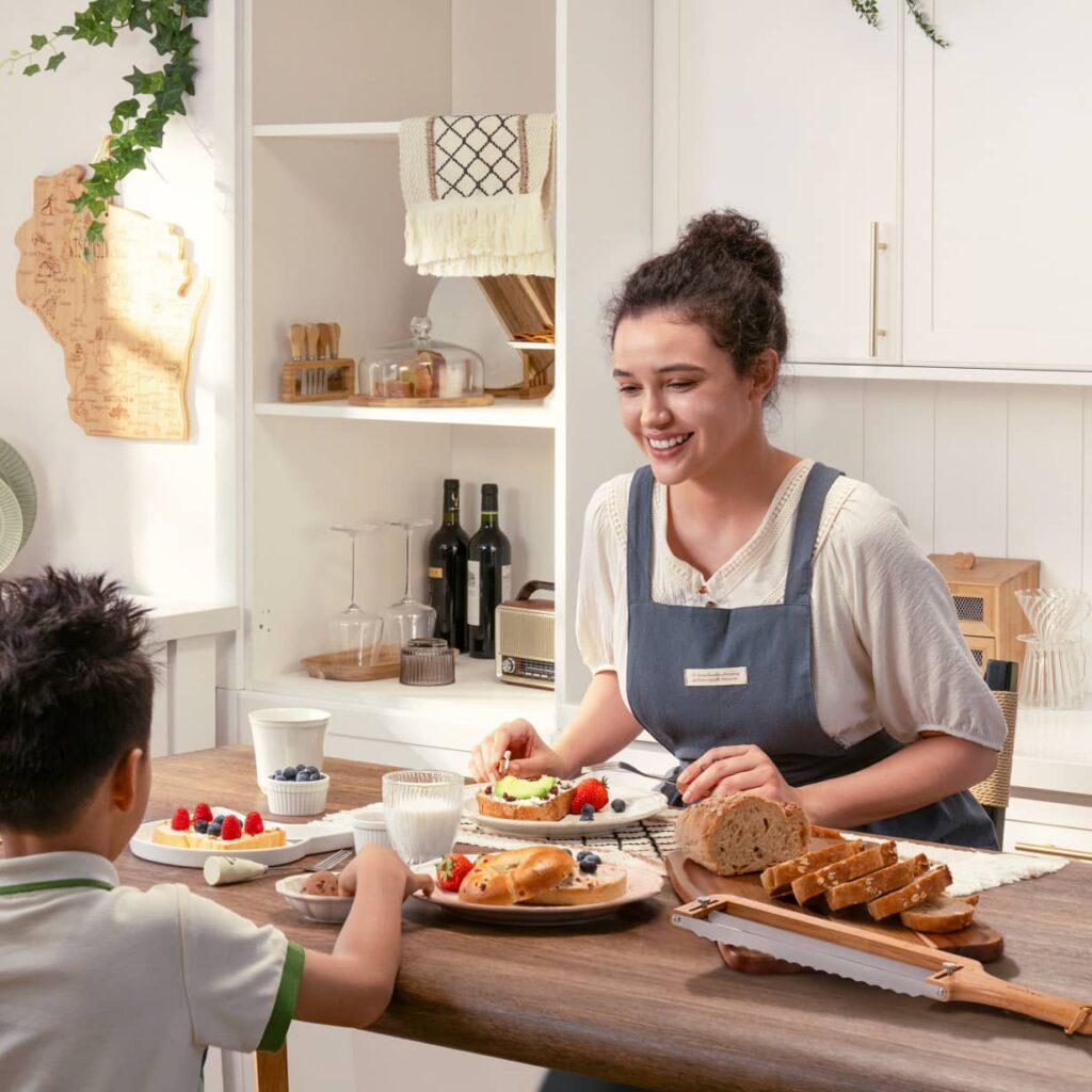 How to Reheat Sourdough Bread: Slices, Half Loaves, and Frozen Bread Adult and child at a kitchen table with sliced bread and a bamboo bread slicer.